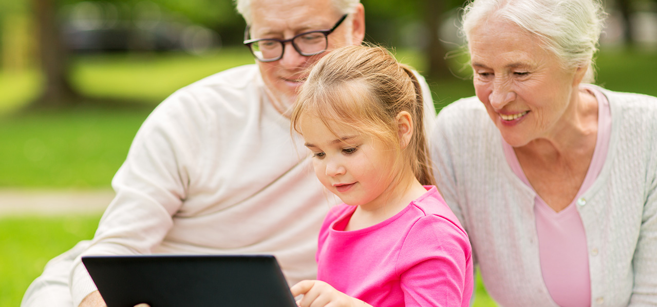 grandparents playing on a tablet with their granddaughter